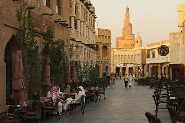 Alt: Khu chợ Souq Waqif nhộn nhịp với nhiều cửa hàng và người mua bán.