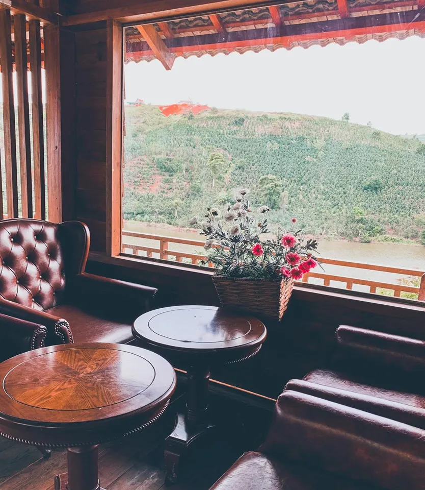 Alt: Khung cảnh bình yên tại Mộc Trà Farm Đà Lạt với bàn ghế gỗ mộc mạc nhìn ra đồi chè xanh mướt
