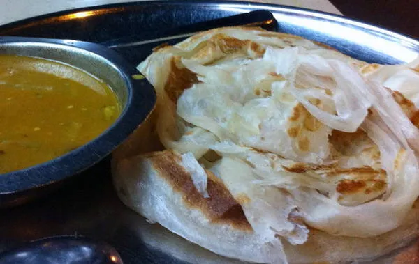 alt text: Bánh tráng Roti Canai được chiên vàng giòn trên một chiếc chảo lớn