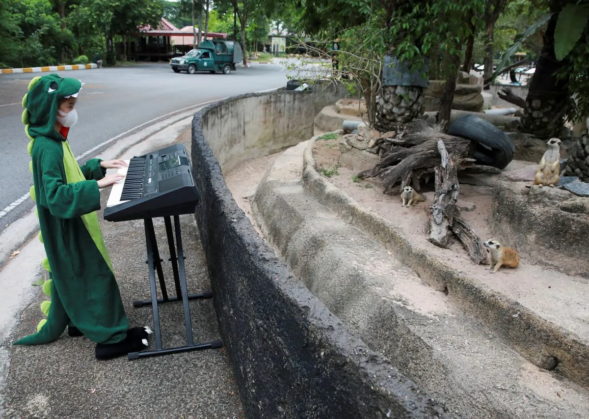 alt text: Cô bé Seenlada Supat chơi đàn guitar cho động vật tại sở thú Khao Kheow Open Zoo