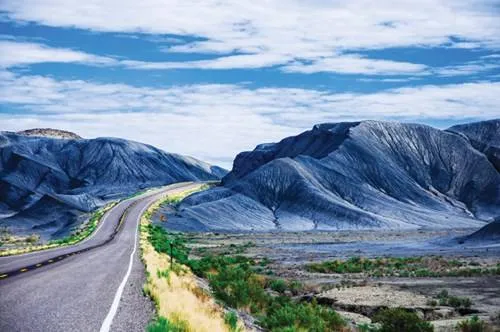 alt text: Con đường vắng vẻ chạy xuyên qua bang Utah, hai bên là những ngọn núi đá đỏ