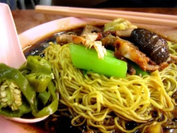 alt text: Đĩa mì Wonton Mee với mì vàng, rau xanh và ớt ngâm