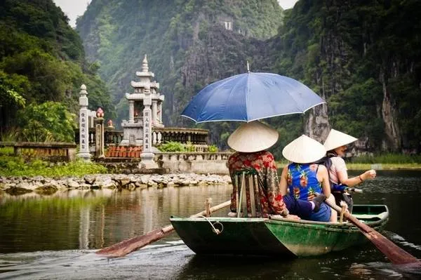 Alt text: Du khách chèo thuyền trên sông Ngô Đồng tại Tam Cốc, Ninh Bình. Cảnh vật yên bình với núi non hùng vĩ và dòng sông xanh biếc tạo nên một bức tranh thiên nhiên tuyệt đẹp.