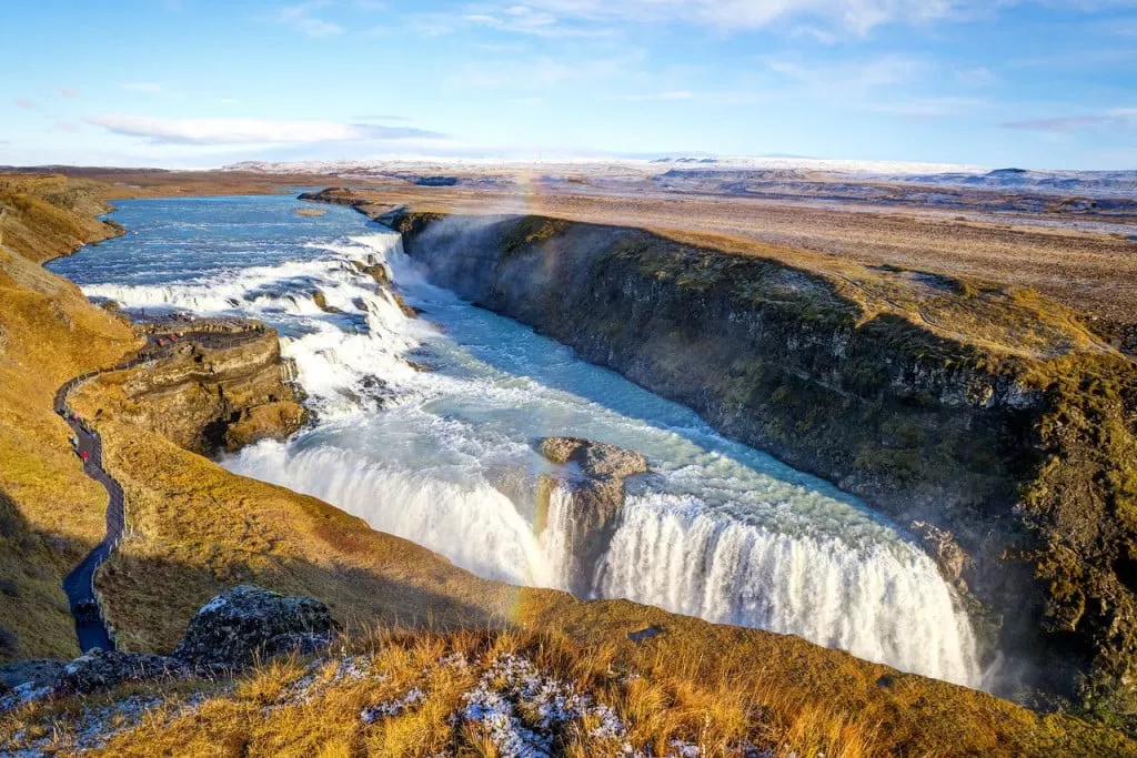 alt text: Du khách đứng trên một mỏm đá gần thác nước Gullfoss, chiêm ngưỡng vẻ đẹp hùng vĩ của thiên nhiên.
