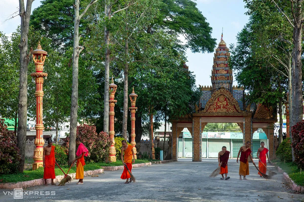 alt text: Hàng rào kiên cố bao quanh chùa Xiêm Cán với hoa văn tinh xảo và cây xanh thẳng tắp hai bên lối vào.