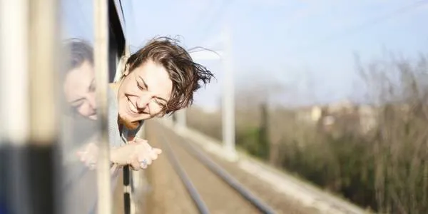 Alt text: Hình ảnh một người phụ nữ đang ngồi trên vali và nhìn ra biển, thể hiện mong muốn được đi du lịch.