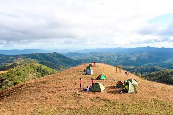 alt text: Nhóm bạn trẻ đang quây quần bên lửa trại, chuẩn bị bữa tối sau một ngày trekking mệt mỏi. Không khí ấm áp và vui vẻ giữa thiên nhiên hoang sơ tạo nên những kỷ niệm khó quên.