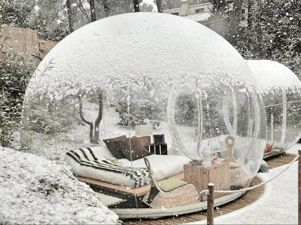 alt text: Nội thất bên trong phòng bong bóng Glamour Bubble tại Attrap'Rêves, được trang trí lãng mạn với nến và hoa hồng