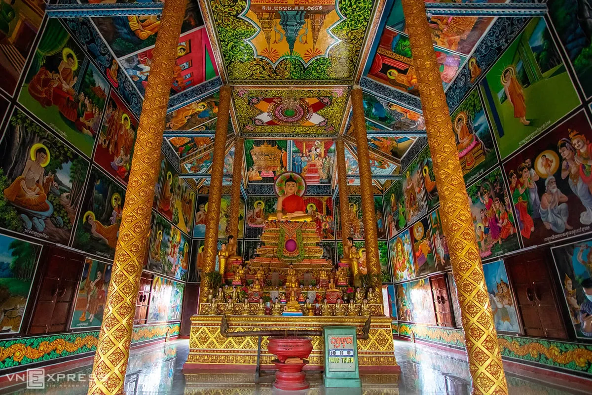 alt text:  Nội thất chánh điện chùa Xiêm Cán với bệ thờ Phật Thích Ca và nhiều bích họa trang trí.