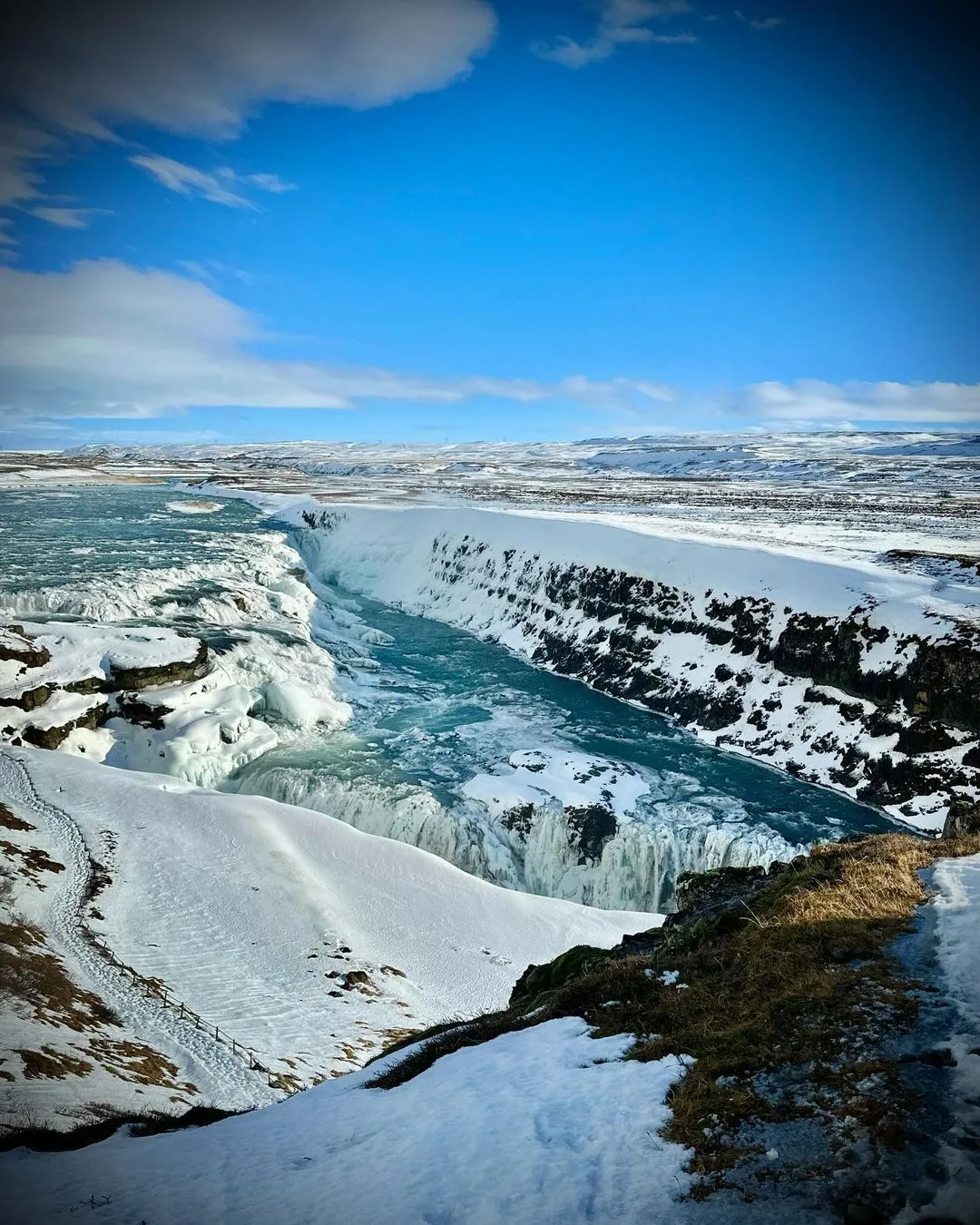 alt text: Thác nước Gullfoss hiện lên trong một ngày tuyết rơi, dòng nước trắng xóa tương phản với màu trắng của tuyết, tạo nên một bức tranh thiên nhiên tuyệt đẹp.