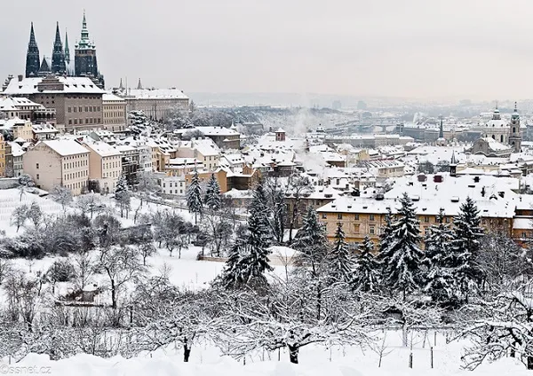 alt text: Thành phố Prague, Cộng hòa Séc, với những cây cầu cổ kính bắc qua sông Vltava, những tòa nhà lịch sử và những quảng trường rộng lớn. Tuyết trắng phủ kín mọi cảnh vật, tạo nên một khung cảnh yên bình và lãng mạn.