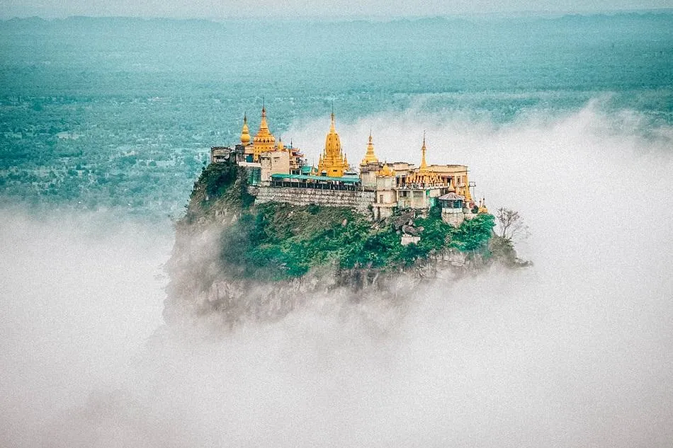 alt text: Tu viện Taung Kalat trên đỉnh núi lửa ở Myanmar, với những tòa tháp dát vàng nổi bật giữa mây trời