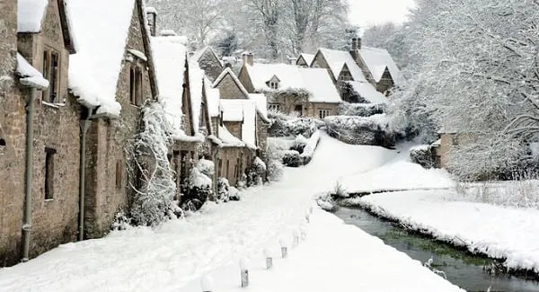alt text: Vùng Cotswolds, Anh, với những ngôi làng cổ kính, những cánh đồng xanh mướt và những ngọn đồi tho缓 uốn lượn. Tuyết trắng phủ lên toàn bộ khung cảnh, tạo nên một vẻ đẹp thanh bình và tĩnh lặng.