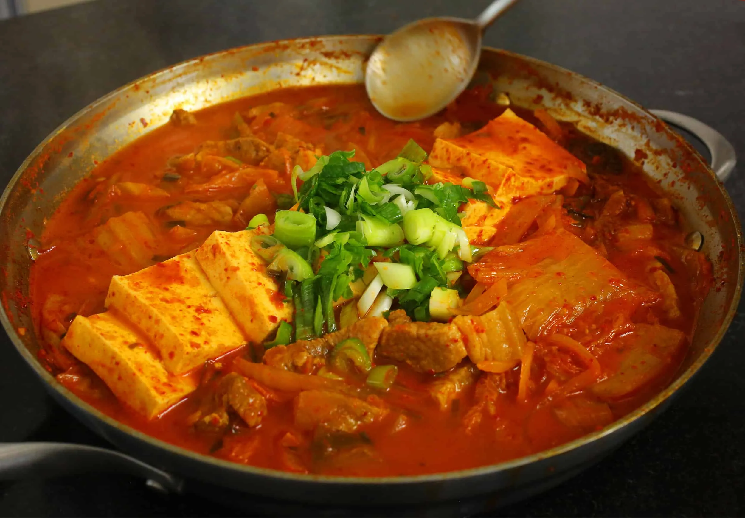 Alt: Tô canh Kimchi Jjigae nóng hổi, màu đỏ bắt mắt