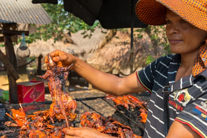 Chuột đồng nướng trên bếp than hồng. Alt: Món chuột đồng nướng thơm phức, ăn kèm nước sốt me xoài chua ngọt, đặc sản Campuchia.