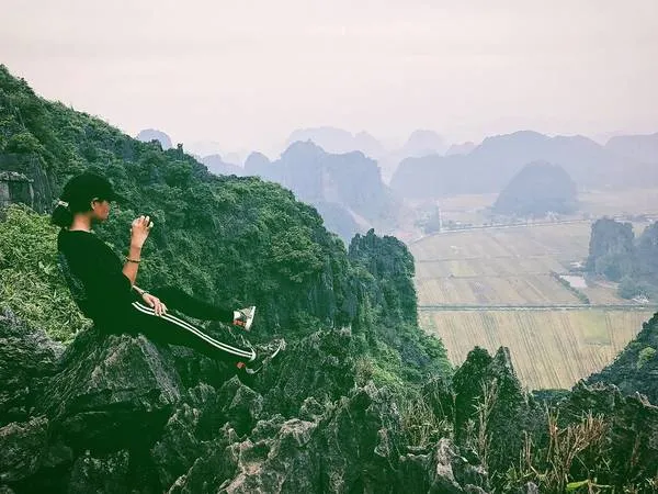 Du khách chụp ảnh check-in trên đỉnh núi Múa với khung cảnh tuyệt đẹp phía sau.