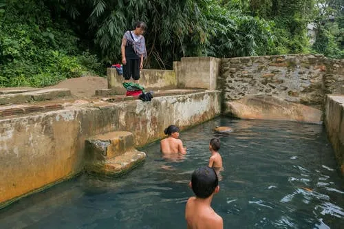 Du khách trò chuyện cùng người dân địa phương tại bể tắm nước khoáng nóng. Ảnh: Tuấn Trần.
