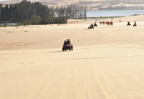 Đua xe địa hình trên đồi cát Khu đồi cát trắng cách Phan Thiết khoảng 40 km, là địa điểm lý tưởng để trải nghiệm đua môtô địa hình 4 bánh, vượt qua nhiều con dốc cát. Nơi đây thu hút đông khách du lịch, đặc biệt là những người trẻ mê khám phá, mạo hiểm. Giá thuê xe môtô cho 2 người từ 350.000 đồng đến 850.000 đồng tùy thời lượng 20-60 phút. Ảnh: Muine-explorer.