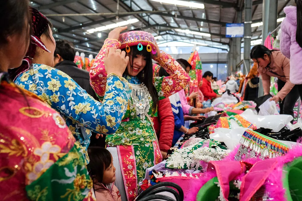 Một cô gái người Mông đang lựa chọn khăn đội đầu tại chợ phiên Mèo Vạc, Hà Giang