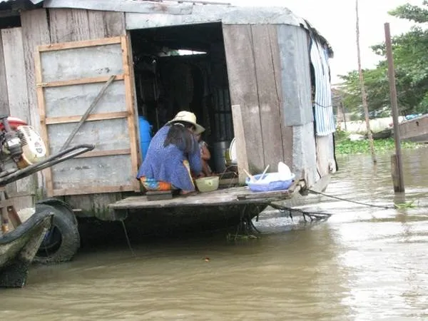 Một gia đình sống trên thuyền với cây bẹo treo nông sản phía trước.