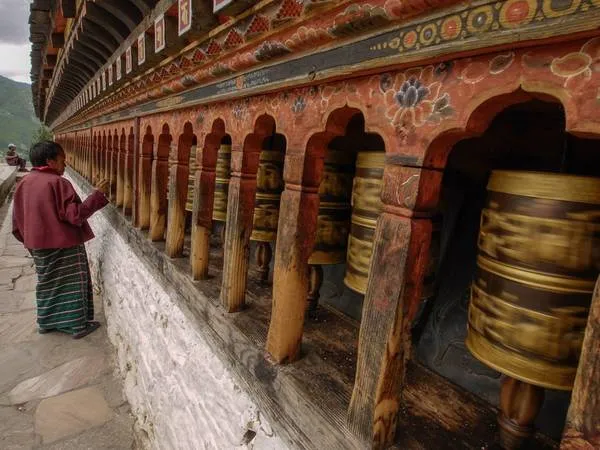 Một tín đồ Phật giáo đang quay bánh xe kinh luân tại một ngôi đền ở Thimphu, thủ đô của Bhutan. Bánh xe kinh luân được cho là mang lại may mắn và bình an cho người quay.