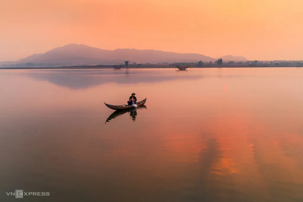 Ngư dân thả lưới trên hồ lúc bình minh. 