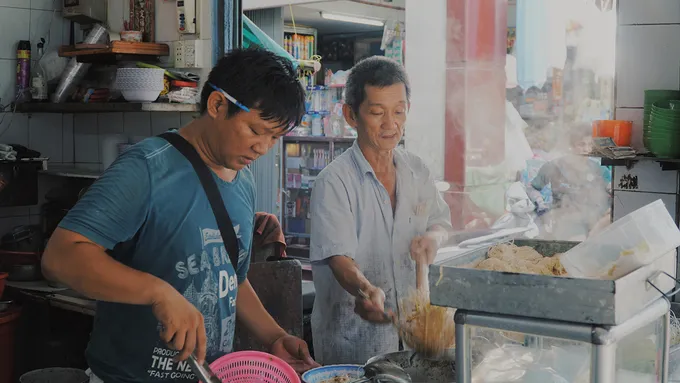 Quầy chế biến hủ tiếu với nồi nước lèo nghi ngút khói và các nguyên liệu được sắp xếp gọn gàng.