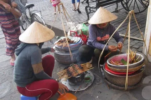 Thịt xiên nướng Hội An được cuốn trong bánh tráng, ăn kèm rau sống chấm nước sốt đậm đà.